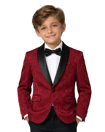 A young boy modeling a formal kids' tuxedo featuring a textured red velvet blazer with black satin lapels, black trousers, a white dress shirt, and a black bow tie, set against a plain white studio background.