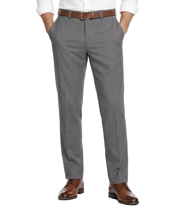 A man modeling a white long-sleeve dress shirt and gray dress pants with a brown belt and brown leather dress shoes, standing against a plain white studio background.