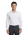 A man wearing a white long-sleeve button-down dress shirt and dark gray trousers, standing against a light gray studio background.