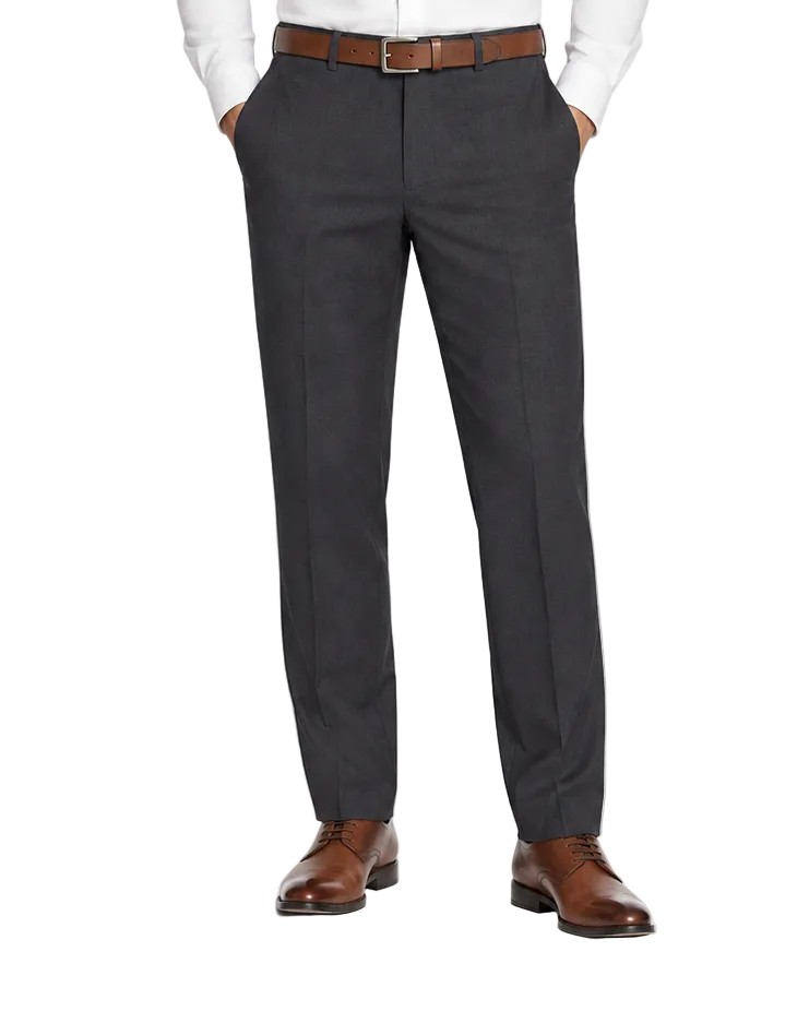 A man modeling a white long-sleeve dress shirt and dark charcoal gray dress pants with a brown belt and brown leather dress shoes, photographed against a seamless white studio background.